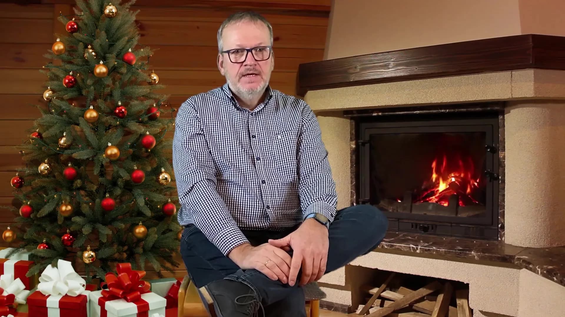 Weihnachtsgruß vor geschmücktem Weihnachtsbaum und Kamin